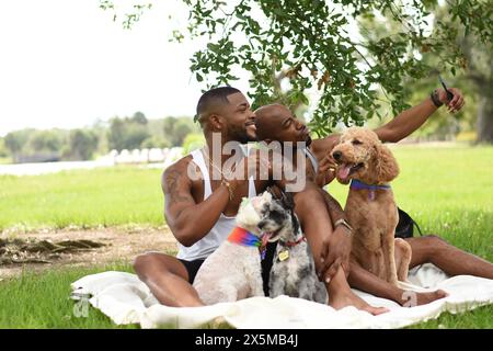 USA, Louisiane, couple gay souriant avec des chiens prenant selfie sur la pelouse dans le parc Banque D'Images