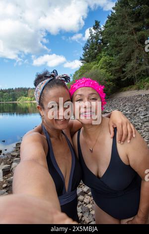 Portrait de femmes souriantes en maillots de bain sur le bord du lac rocheux, Yorkshire, Royaume-Uni Banque D'Images