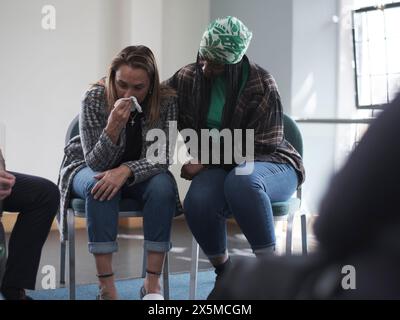 Femme consolant femme pleurant en séance de thérapie de groupe Banque D'Images