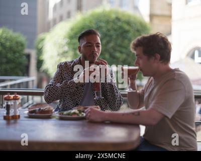 Royaume-Uni, South Yorkshire, couple gay appréciant des cocktails à la table du restaurant Banque D'Images