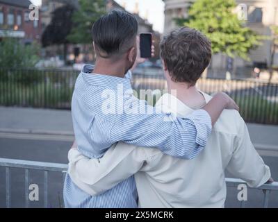 Royaume-Uni, South Yorkshire, vue arrière d'un couple gay prenant selfie à l'extérieur Banque D'Images