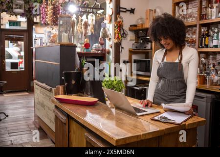 Royaume-Uni, Londres, propriétaire de café utilisant un ordinateur portable au comptoir Banque D'Images