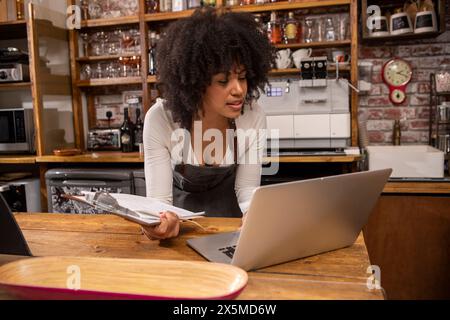 Royaume-Uni, Londres, propriétaire de café utilisant un ordinateur portable au comptoir Banque D'Images