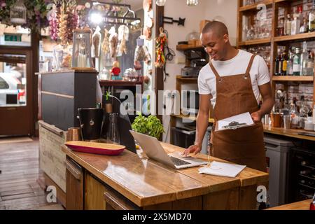 Royaume-Uni, Londres, propriétaire de café utilisant un ordinateur portable au comptoir Banque D'Images