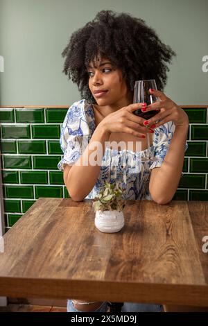 Royaume-Uni, Londres, Pensive femme avec un verre de vin rouge à la table de café Banque D'Images