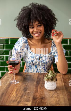 Royaume-Uni, Londres, Portrait de femme souriante avec un verre de vin rouge à la table du café Banque D'Images