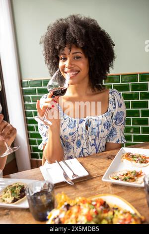 Royaume-Uni, Londres, Portrait de femme souriante appréciant le vin rouge à la table du restaurant Banque D'Images