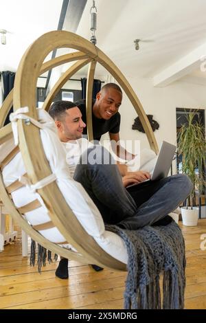 Royaume-Uni, Londres, couple gay souriant utilisant un ordinateur portable dans le salon Banque D'Images