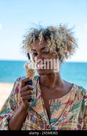 Portrait d'une femme souriante mangeant de la crème glacée Banque D'Images