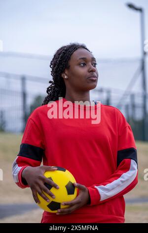 Portrait de femme sportive pensive avec ballon de football Banque D'Images