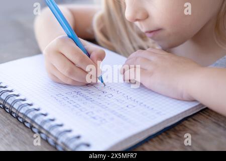 La main de l'enfant écrit avec un stylo dans un cahier, pratique de l'écriture manuscrite pour préscolaire, développement de la main, pratique de l'écriture manuscrite pour préscolaire Banque D'Images