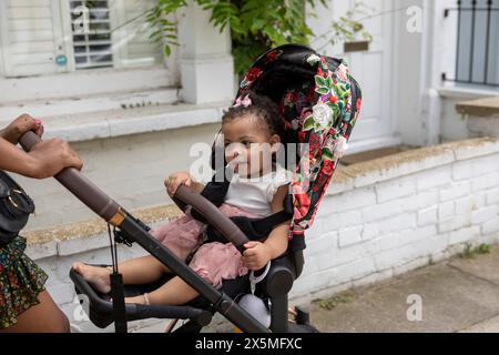 Mère allant pour la promenade avec bébé fille (12-17 mois) en poussette Banque D'Images