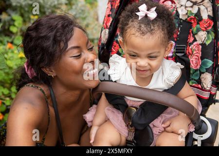 Mère allant pour la promenade avec bébé fille (12-17 mois) en poussette Banque D'Images