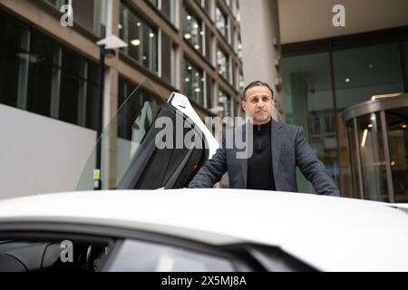 Homme mûr appuyé contre la voiture de luxe Banque D'Images