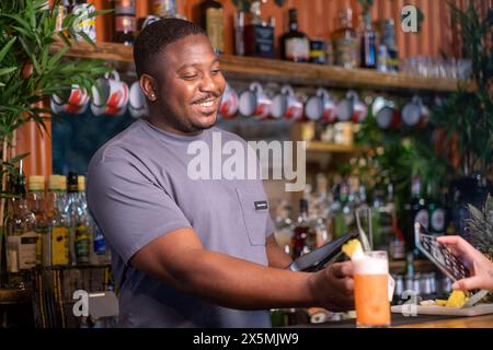 Barman souriant avec lecteur de voiture de crédit et tablette au bar, USUN wiek kobiety Banque D'Images