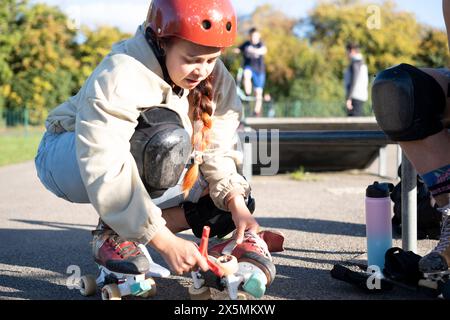 Femme se préparant à patiner à roulettes dans le parc de skate Banque D'Images