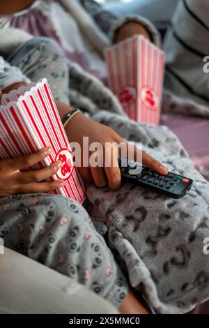 Gros plan de sœurs tenant la télécommande et du pop-corn Banque D'Images