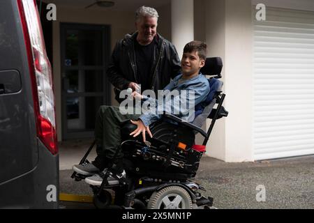 Père et fils handicapés utilisant un ascenseur pour fauteuil roulant Banque D'Images