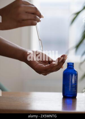 Gros plan des mains de femmes tenant une pipette avec sérum facial Banque D'Images