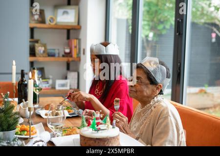 Femmes portant des couronnes en papier profitant du dîner de Noël Banque D'Images