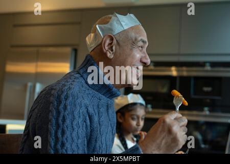 Homme souriant portant une couronne de papier appréciant le dîner de Noël Banque D'Images