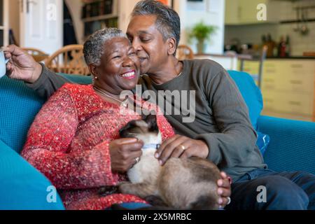 Couple senior avec chat assis sur le canapé Banque D'Images