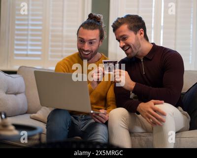 Couple gay montrant l'échographie d'un bébé lors d'un appel vidéo à la maison Banque D'Images