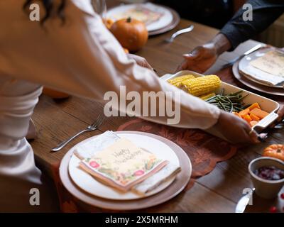 Femme mettant un plat de casserole avec des légumes sur la table de Thanksgiving Banque D'Images