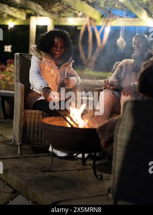 Homme et femme assis près de la fosse de feu sur le patio Banque D'Images