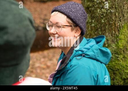 Femme souriante se relaxant dans la forêt Banque D'Images