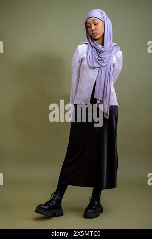 Portrait d'une jeune femme en hijab debout sur fond vert Banque D'Images