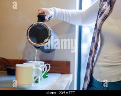 Femme versant de l'eau dans la tasse de thé Banque D'Images