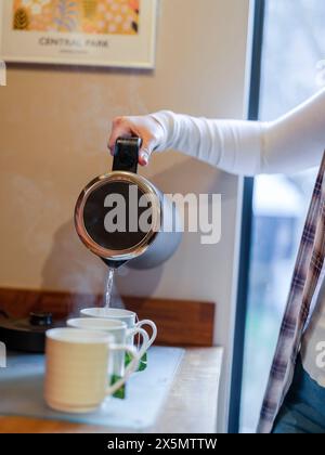 Femme versant de l'eau dans la tasse de thé Banque D'Images