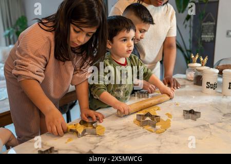 Maman avec des enfants préparant des biscuits de Noël dans la cuisine Banque D'Images