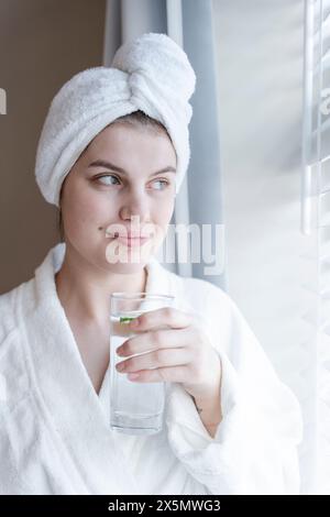 Portrait de femme en peignoir et serviette turban avec verre d'eau Banque D'Images