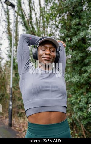 Femme athlétique étirant le bras dans le parc Banque D'Images