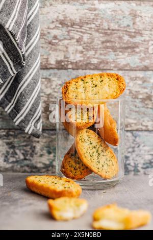Tranches de pain croustillant à l'ail surmontées d'herbes dans un pot sur une table de cuisine. Banque D'Images