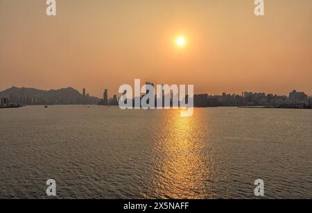 Coucher de soleil sur les gratte-ciel de Hong Kong au port Victoria, mer, reflet Banque D'Images