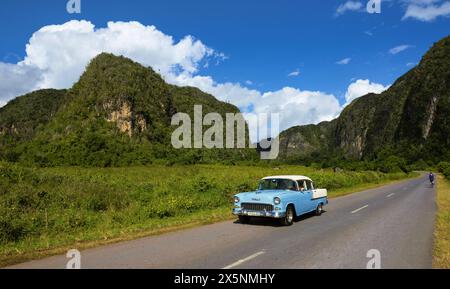 Une voiture et un cycliste traversent la vallée de Vinales à Cuba Banque D'Images