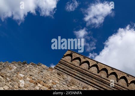 Détails sur la façade d'un bâtiment dans la ville médiévale historique de San Gimignano en Toscane, Italie par une journée ensoleillée avec ciel bleu et nuages blancs. Banque D'Images