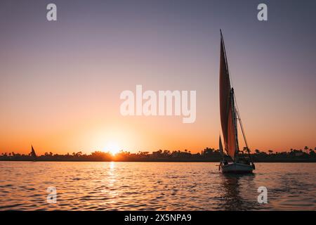 Les voiliers se prélassent dans la lumière dorée du coucher du soleil sur le Nil près de Louxor, en Égypte Banque D'Images