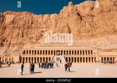 Les touristes visitent le temple mortuaire de Hatshepsout à Deir el-Bahari, construit dans les falaises de la rive ouest de Louxor, avec la lumière du soleil et le SK bleu clair Banque D'Images