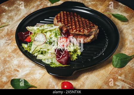 Steak grillé servi avec salade fraîche du jardin sur une assiette noire Banque D'Images