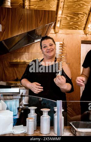 Leipzig, Allemagne. 09.06. 2019. jeune femme de taille plus souriante et tenant des chips tornade spirale de pomme de terre à vendre dans sa main Banque D'Images