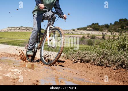 Un homme fait du vélo sur une route boueuse. Le vélo est recouvert de boue. La scène est aventureuse et excitante Banque D'Images