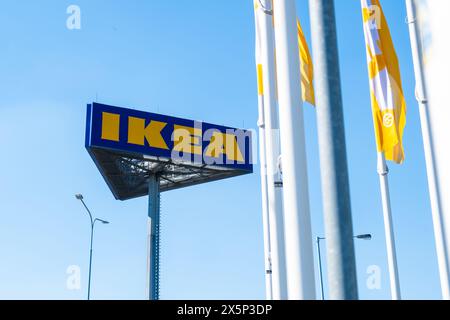 PRAGUE, TCHÉQUIE -AVRIL, 2024 : logo IKEA contre le ciel bleu et les drapeaux. Banque D'Images