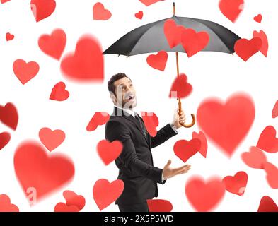 Homme avec parapluie sous la pluie de cœurs isolé sur fond blanc Banque D'Images