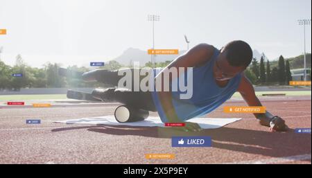 Un homme en forme utilisant un rouleau en mousse sur le terrain de piste pour l'entraînement Banque D'Images