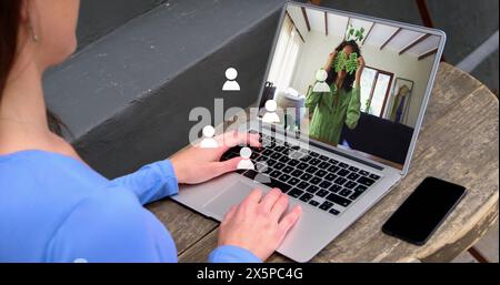 Image d'icônes de profil sur une femme caucasienne ayant un imagecall sur ordinateur portable dans un café Banque D'Images