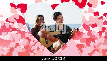 Image de cœurs sur des amis caucasiens heureux avec guitare sur la plage Banque D'Images